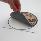 Hand peeling a circular brown caymas boats decal from its backing.