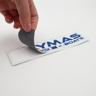 A hand pulling back a small colorful caymas boats logo decal from the transfer paper.